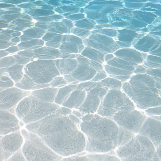 Smooth white plaster pool floor under clear water
